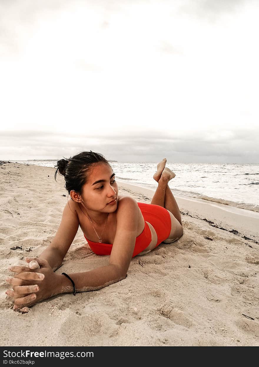 Woman Wearing Red Bikini Laying On Beach Sand