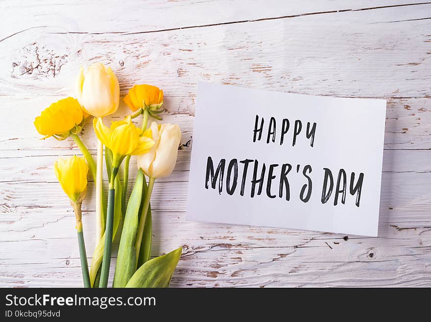 Mothers day composition. Happy mothers day note and bouquet of yellow flowers. Studio shot on white wooden background. Flat lay. Mothers day composition. Happy mothers day note and bouquet of yellow flowers. Studio shot on white wooden background. Flat lay.