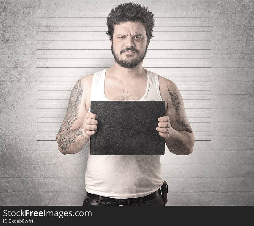 Gangster in front of a wall with table on his hand. Gangster in front of a wall with table on his hand.