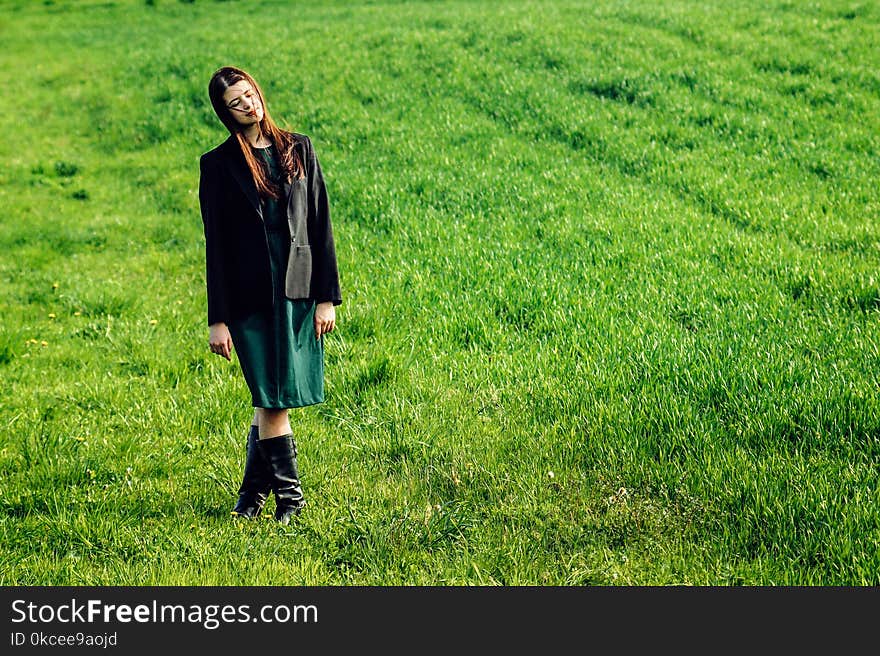 Beautiful brunette girl in windy green field, sunny springtime, environment concept