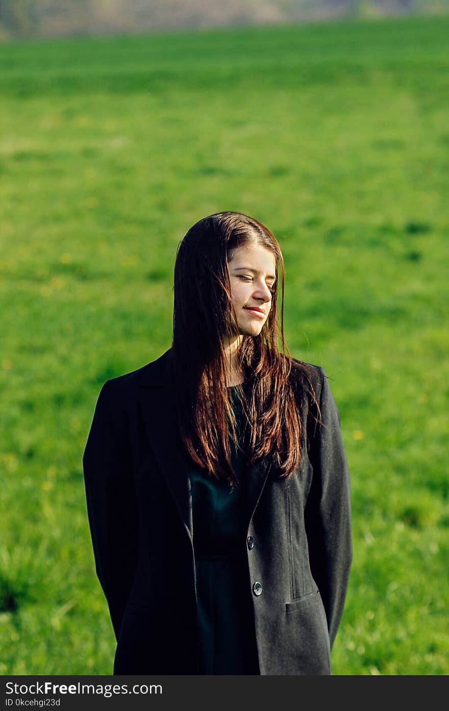 Beautiful brunette girl in windy green field, sunny springtime, environment concept