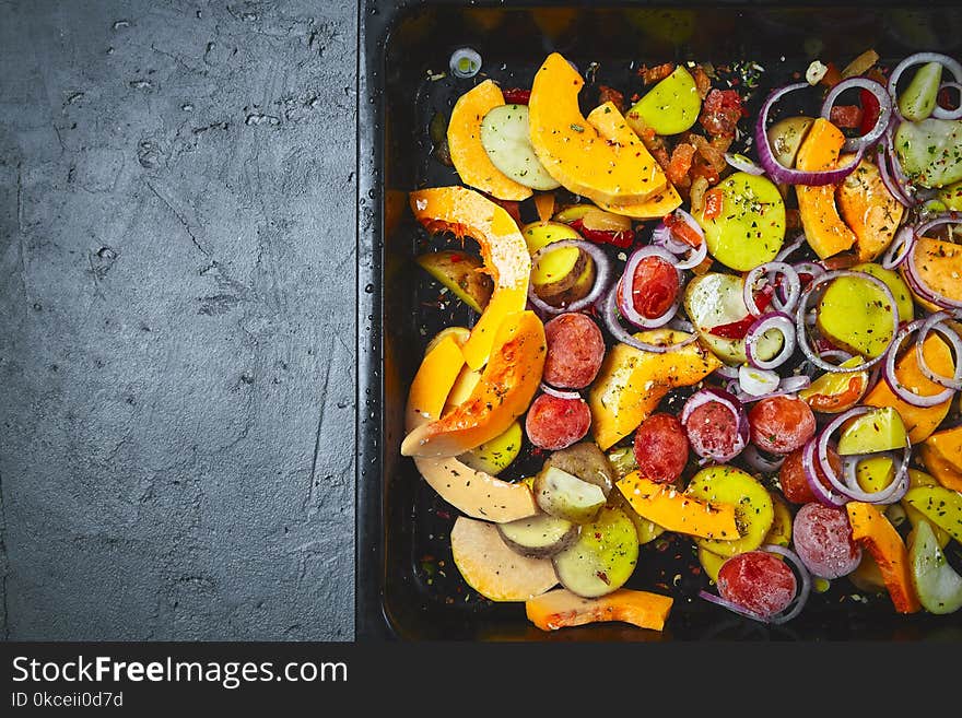 Raw sliced vegetables in baking tray on a black concrete or stone background. Top view .Space for text. Raw sliced vegetables in baking tray on a black concrete or stone background. Top view .Space for text.