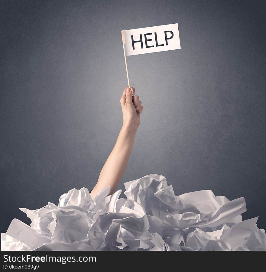 Female hand emerging from crumpled paper pile holding help sign. Female hand emerging from crumpled paper pile holding help sign