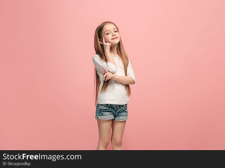 The happy teen girl standing and smiling against pink background.