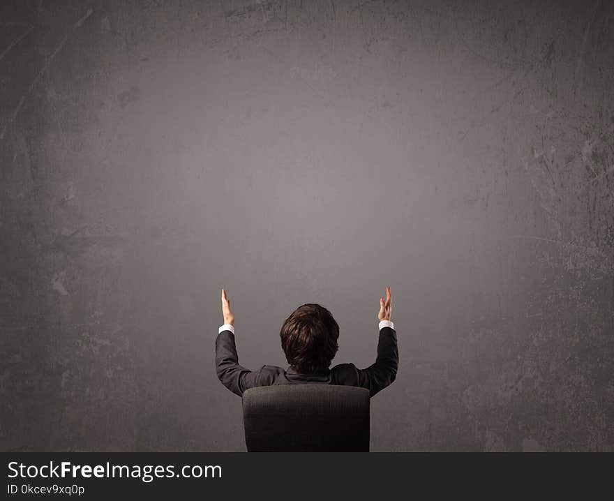 Young businessman sitting in office chair in front of a wall with empty space. Young businessman sitting in office chair in front of a wall with empty space