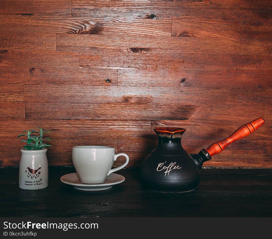 Black and Orange Turkish Coffee Pot on Table Near Cup and Saucer