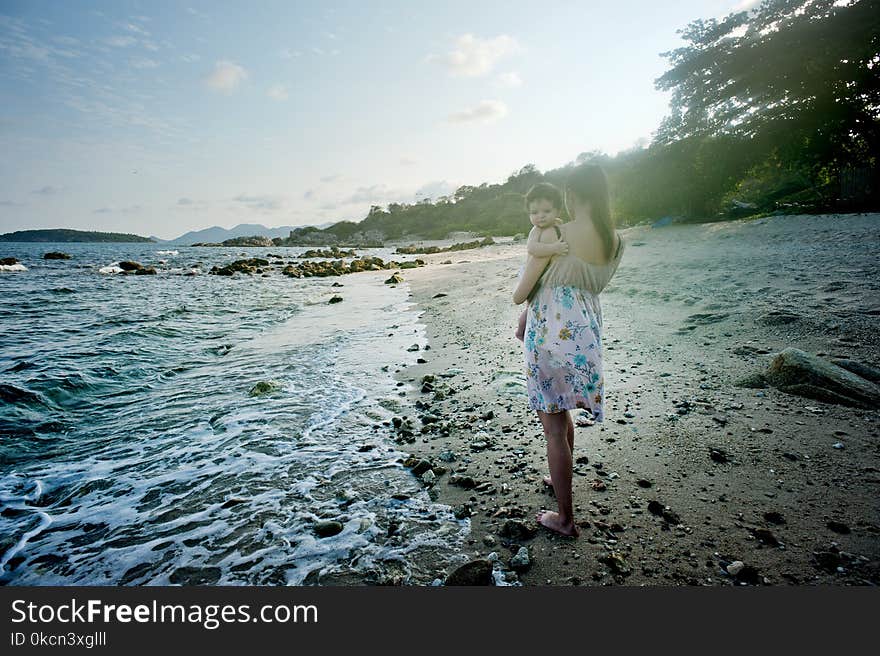 Woman Carrying Baby Beside the Seashore