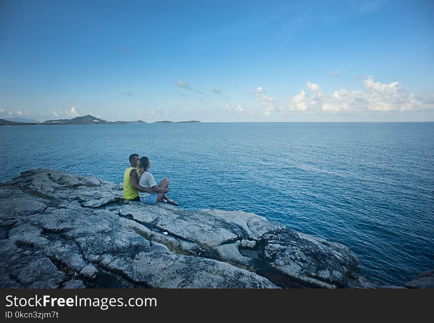 Man and Woman Sitting Near Body of Water