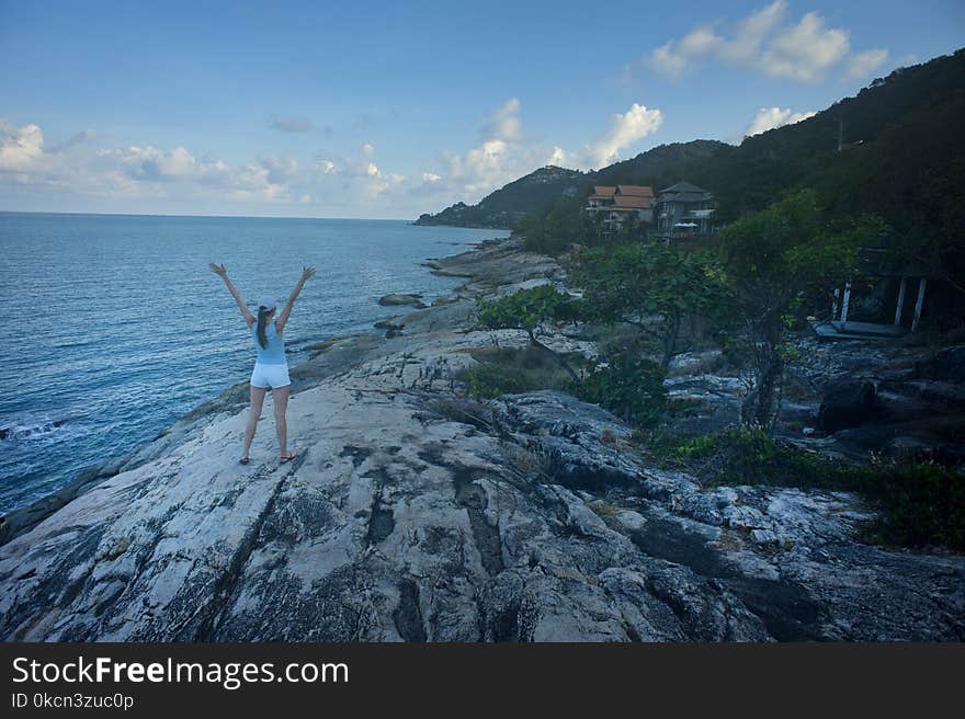 Woman Wearing Blue Tank Top Standing Beside Body of Water