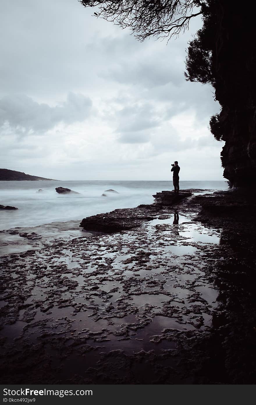 Man Standing on Rock Near Ocean