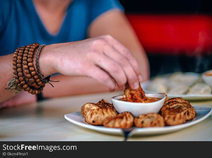 Person Holding Food and Dipping on Sauce