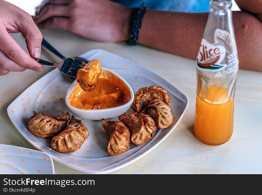 Person in Front of Table With Fried Dumplings and Soda Bottle