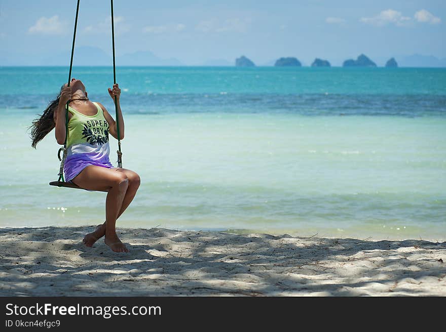 Woman in Green and Purple Tank Top Sitting on Brown Swing