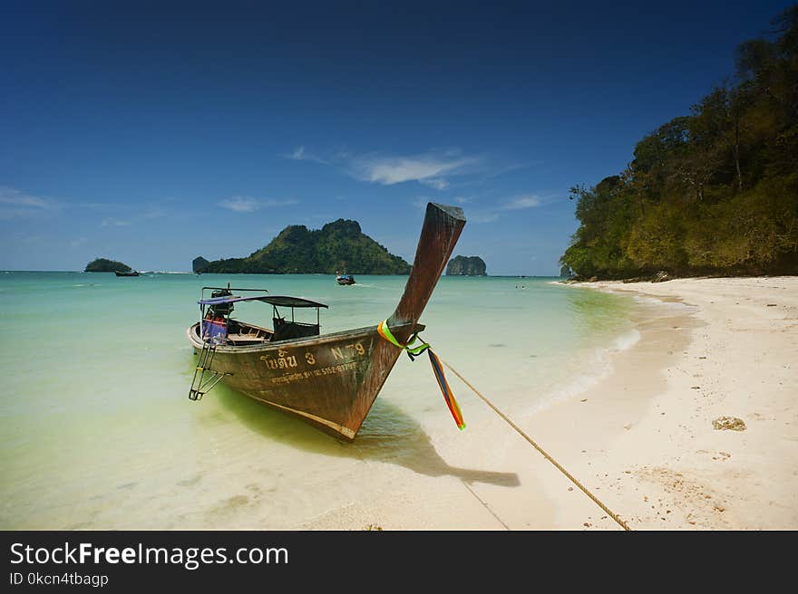 Brown Wooden Boat Beside Body of Water