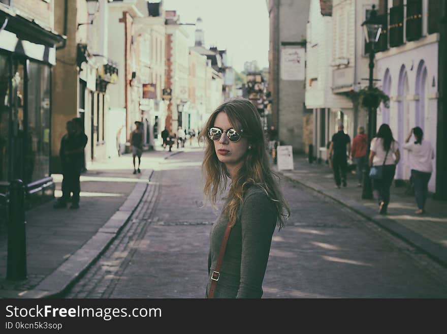 Woman Wearing Gray Long-sleeved Shirt Standing in the Middle of Pavement