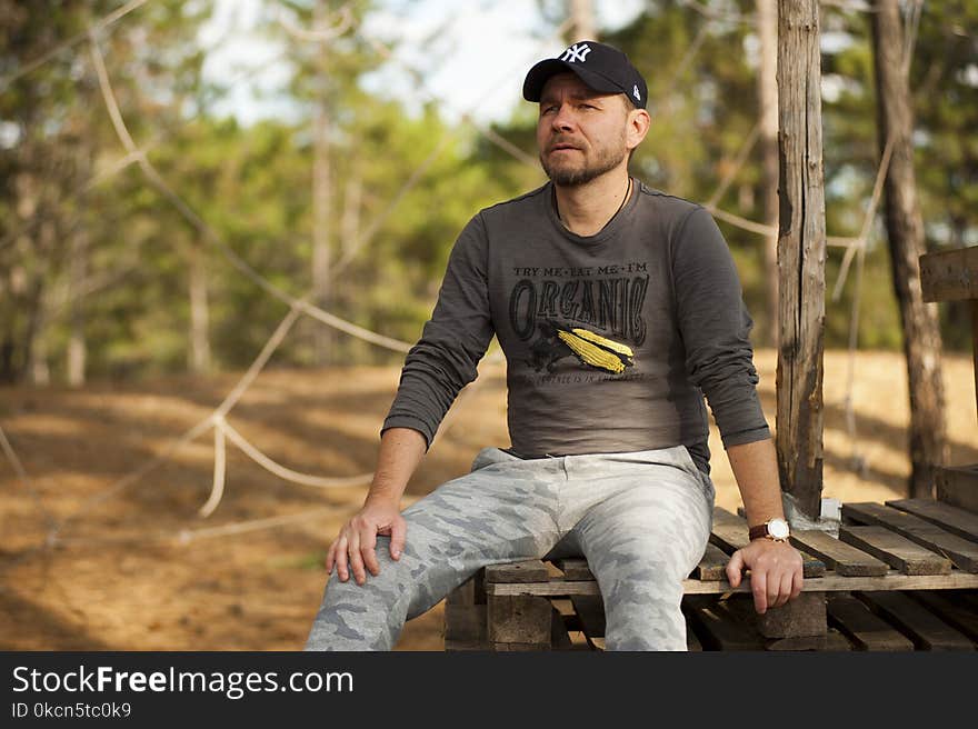 Selective Focus Photo of Man Sitting on Plank