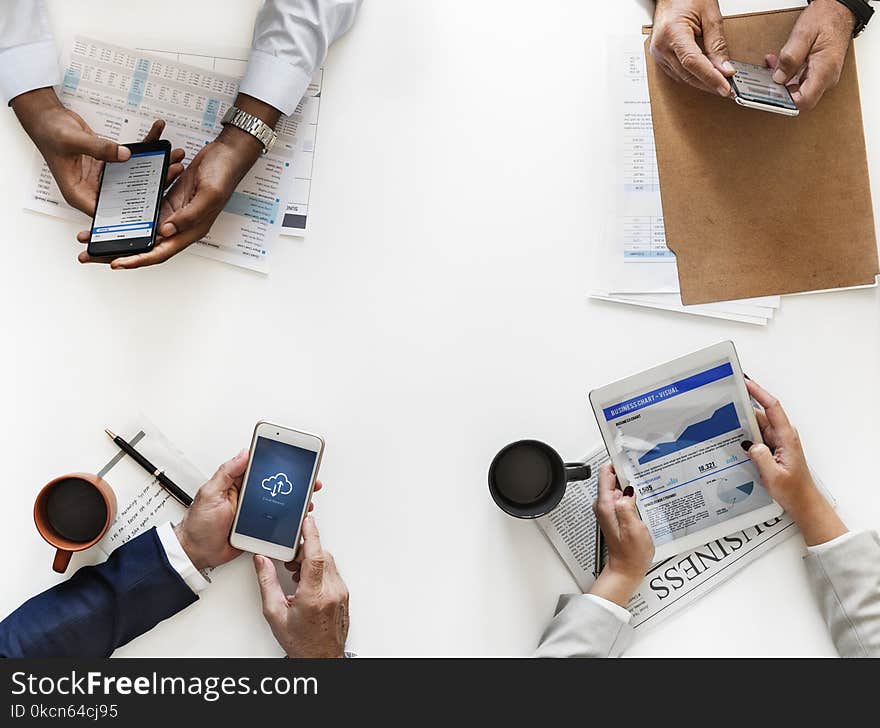 Closeup Photo of Three Persons Hands on Table Holding Smartphones