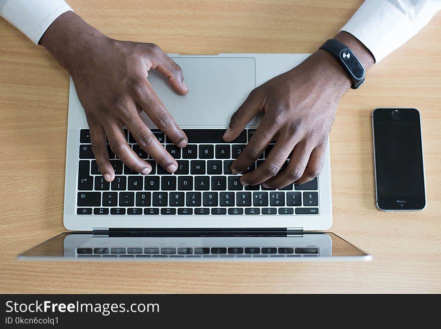 Closeup Photo of Person&#x27;s Hands on Macbook Beside Space Gray Iphone 5s