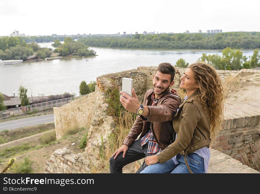 Woman And Man Sitting Against Body Of Water