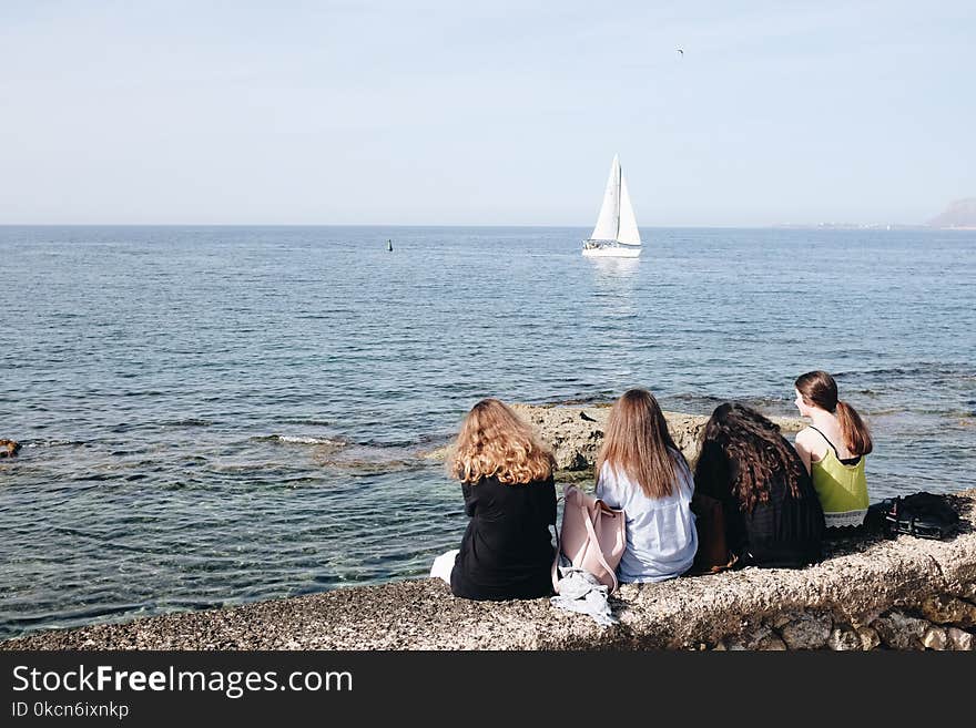 Four Women Sitting Near Sea At Daytime