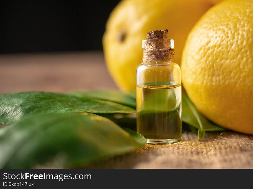 Bottles with Essential Oil of Lemon peel and leaf on wooden table