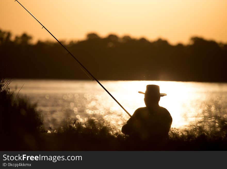 Fisherman with a fishing rod at sunset .