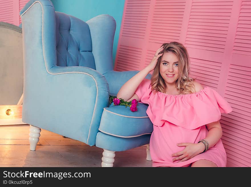 Woman expecting a baby in pink dress in studio