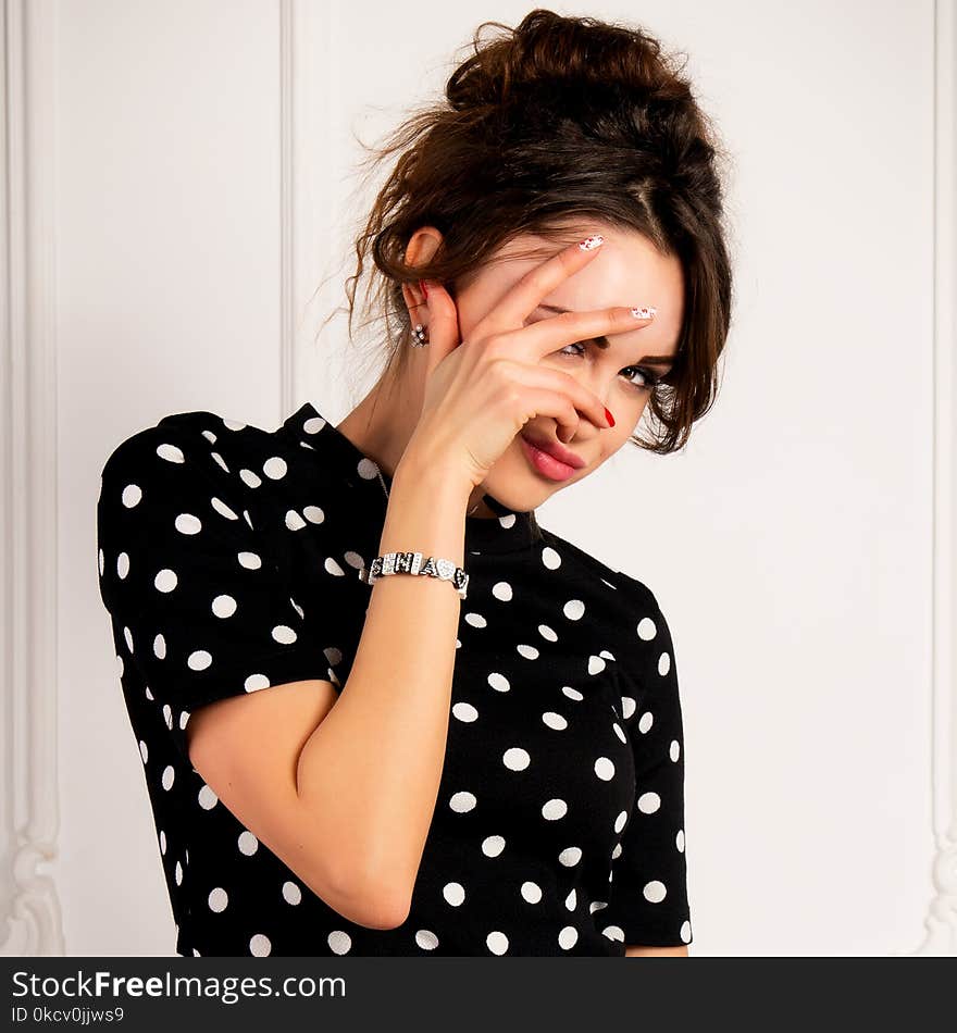 Portrait of a brunette in a black dress on light background in studio