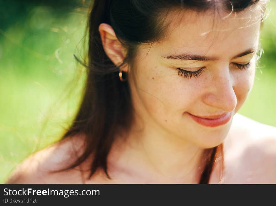 Happy cute woman smiling in sunlight on background of green nature in mountains in summer