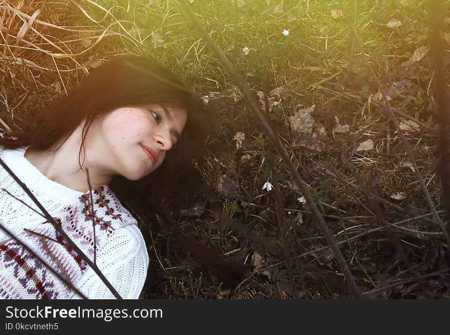 Stylish brunette girl traveler lying with snowdrops on the background of mountains in spring time