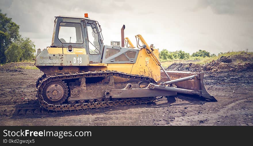 Yellow and Brown Metal Pay Loader on He Dirt