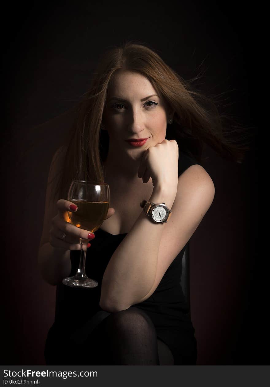 Woman Wearing Black Dress Holding Clear Wine Glass in Dark Room