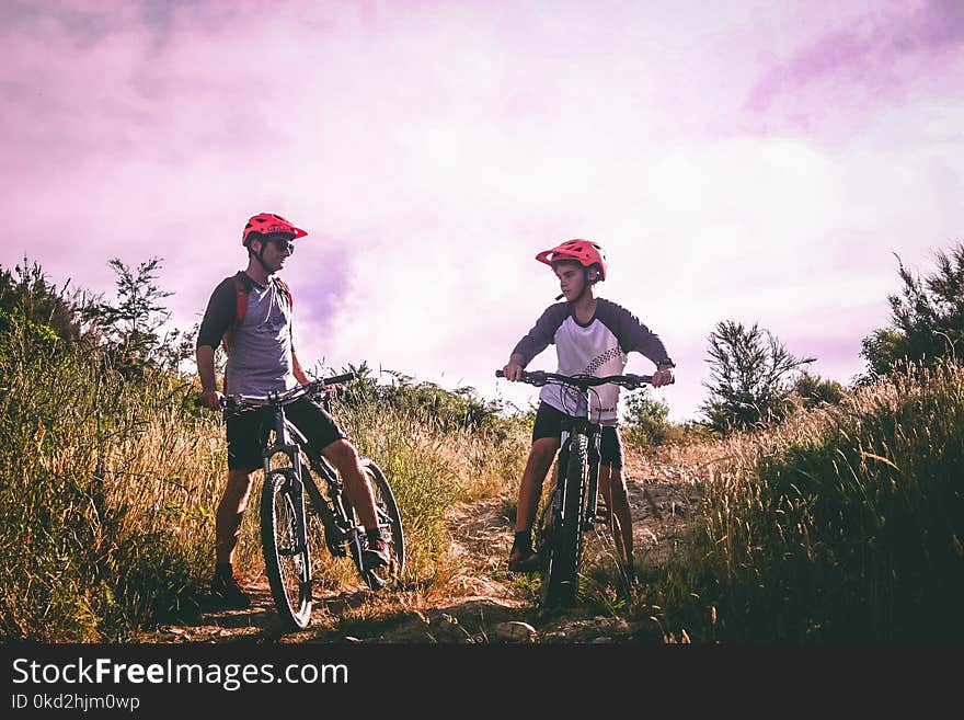 Two Man Riding Mountain Bike on Dirt Road at Daytime