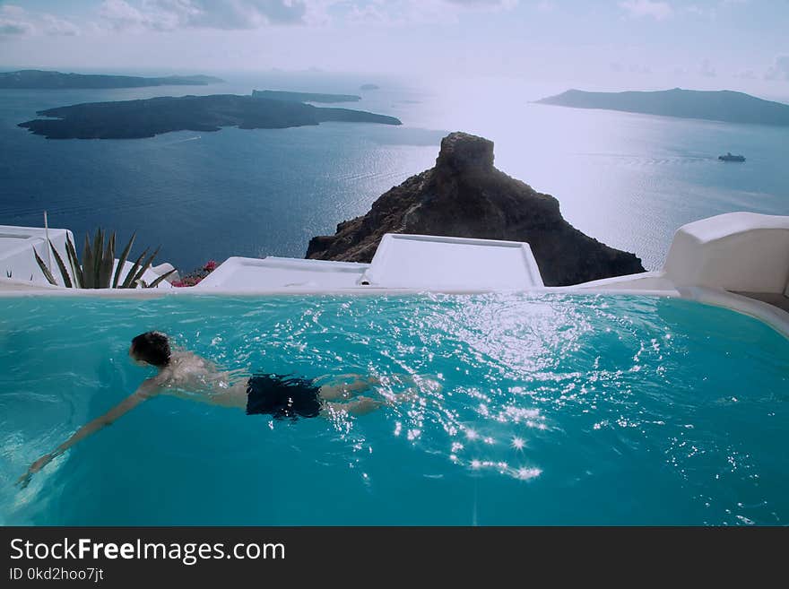 Man Wearing Black Shorts Swimming in Infinity Pool