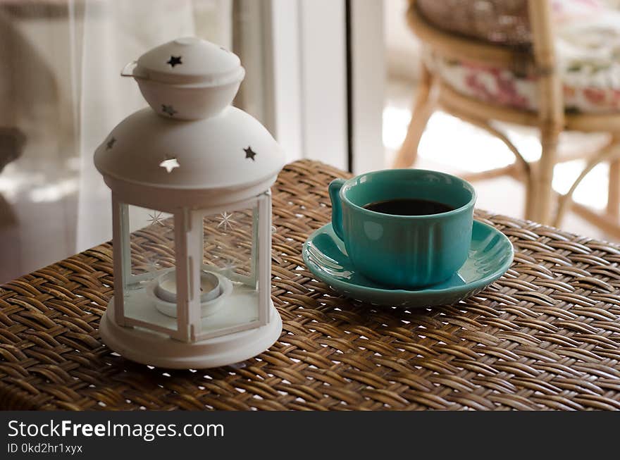 White Candle Lantern Beside of Blue Ceramic Coffee Mug on Wicker Table