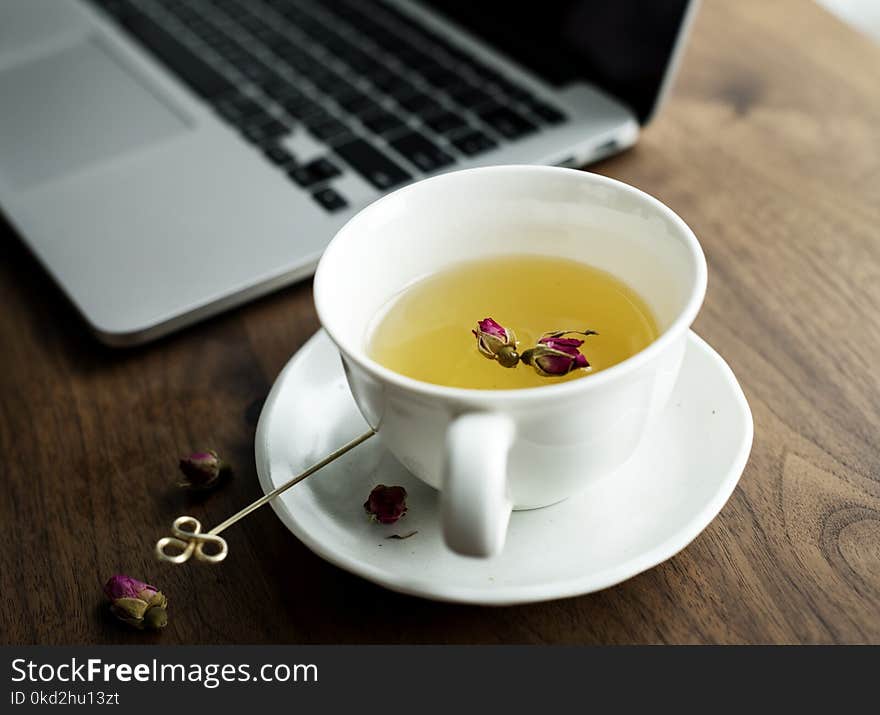 White Ceramic Teacup on Saucer Beside Laptop Computer