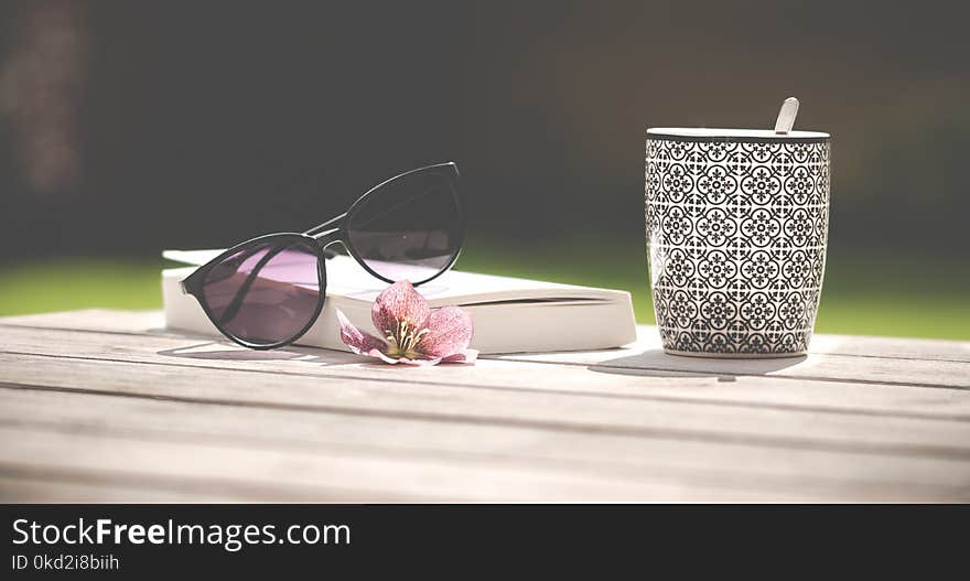 Photo of Black Sunglasses Beside Ceramic Mug