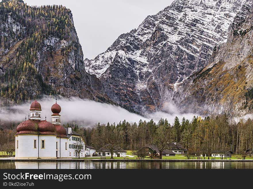 White and Brown Mosque Beside Body of Water Near Rocky Mountain