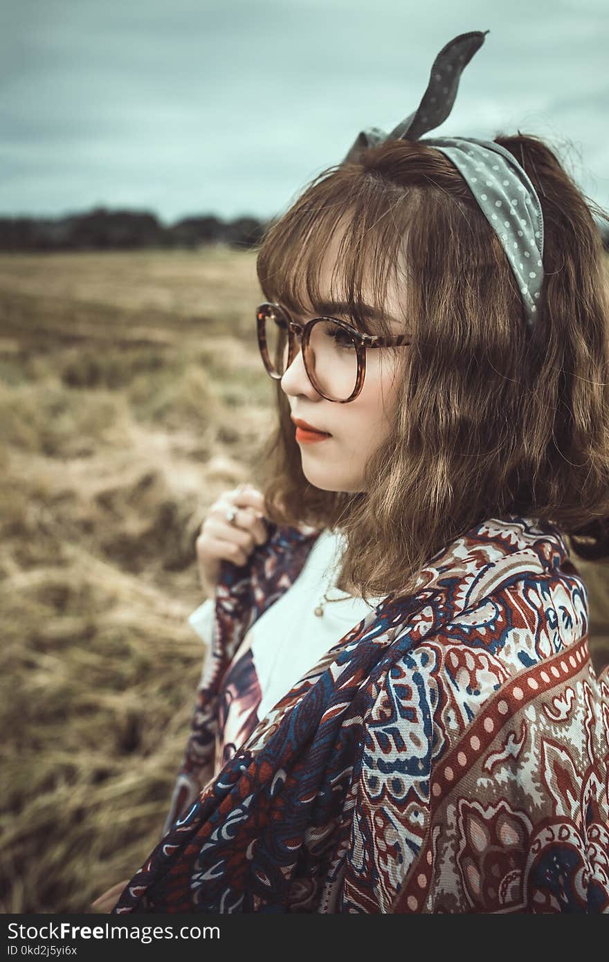 Selective Focus Shot of Woman in White and Brown Floral Standing on Grass Field