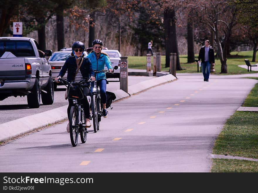 Two Man and Woman Riding Bicycles on Road