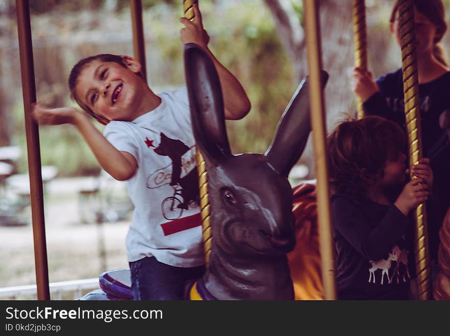 Boy in White T-shirt Riding Carousel