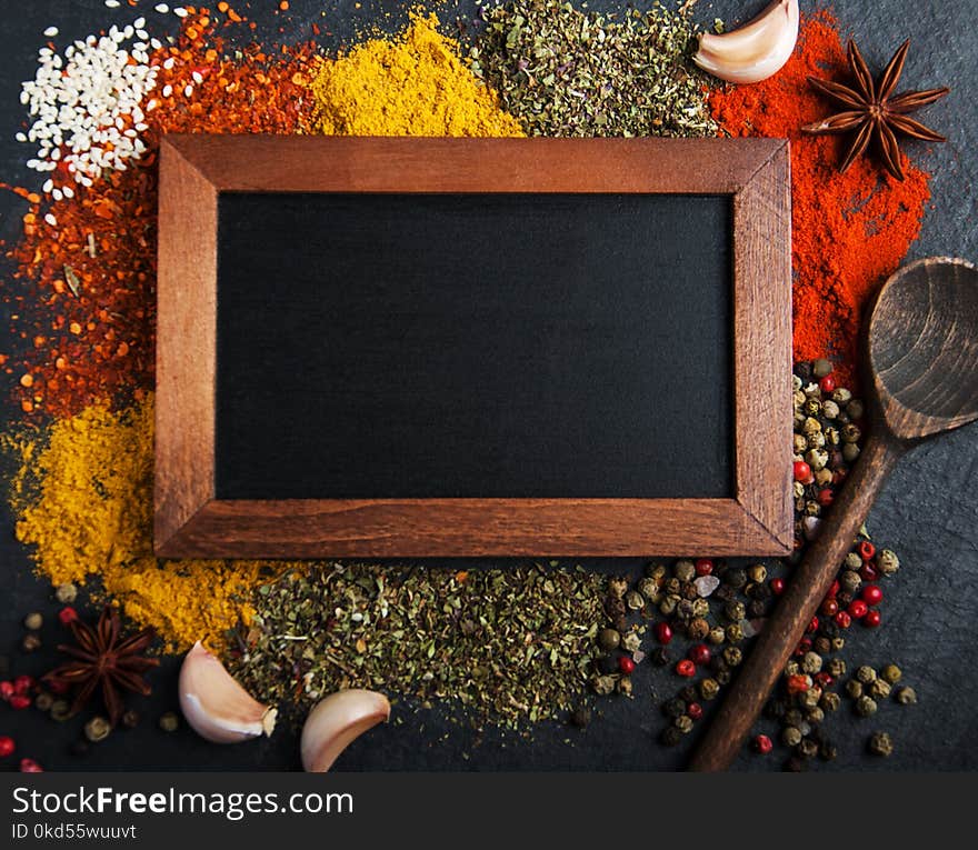 Different kind of spices and blackboard on a black stone background