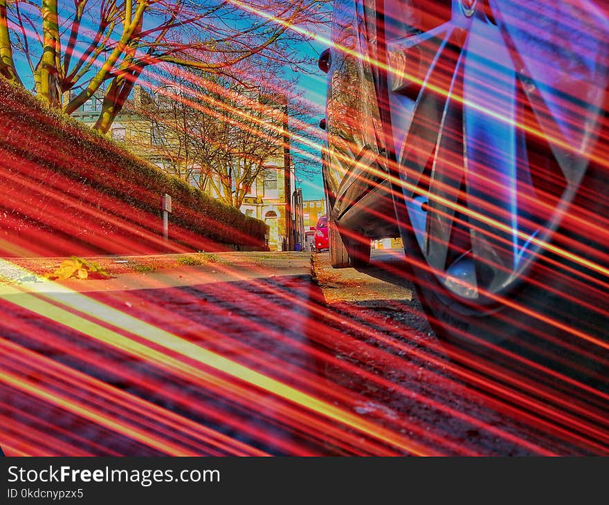 Low angle street view of car wheel taken on a sunny day and layered with a long exposure light flare. Low angle street view of car wheel taken on a sunny day and layered with a long exposure light flare.