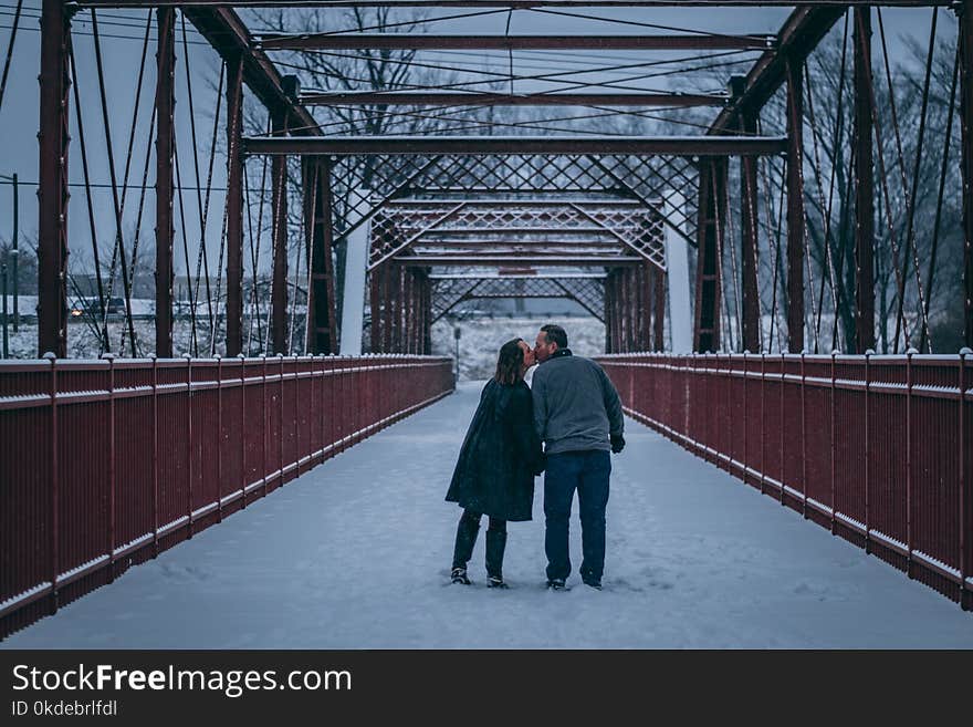 Couple Kissing on Bridge Covered With Snow