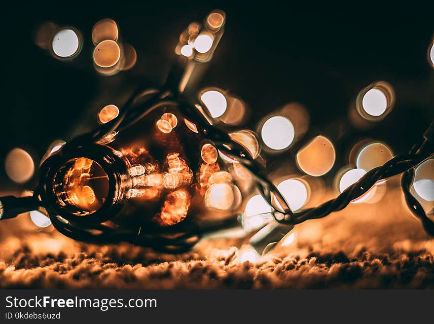 Low-light Photo of Amber Glass Bottle With String Lights and Beige Bokeh