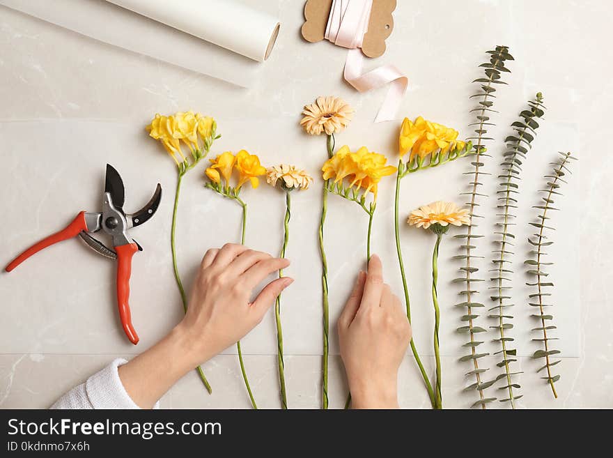 Female florist making beautiful bouquet at table, top view