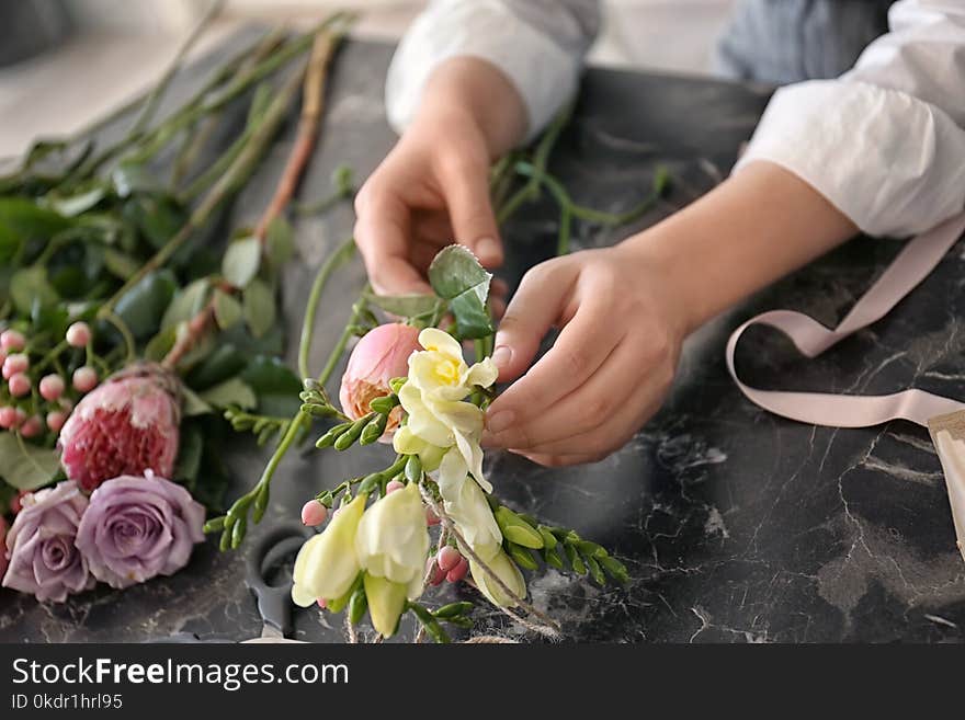 Female florist creating beautiful bouquet at table