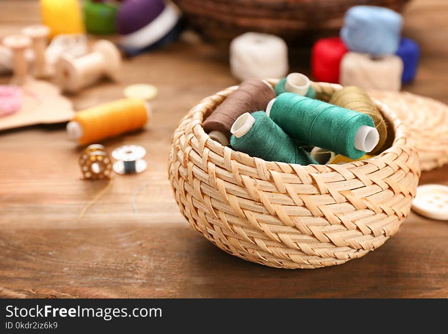 Small box with set of color sewing threads on wooden background