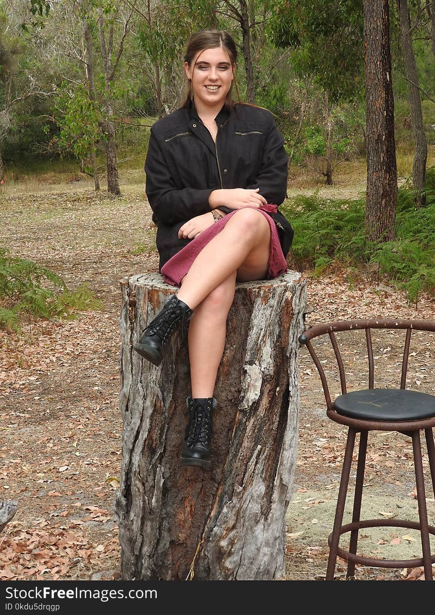 Woman Wearing Black Jacket Sitting on Tree Log Near Bar Stool