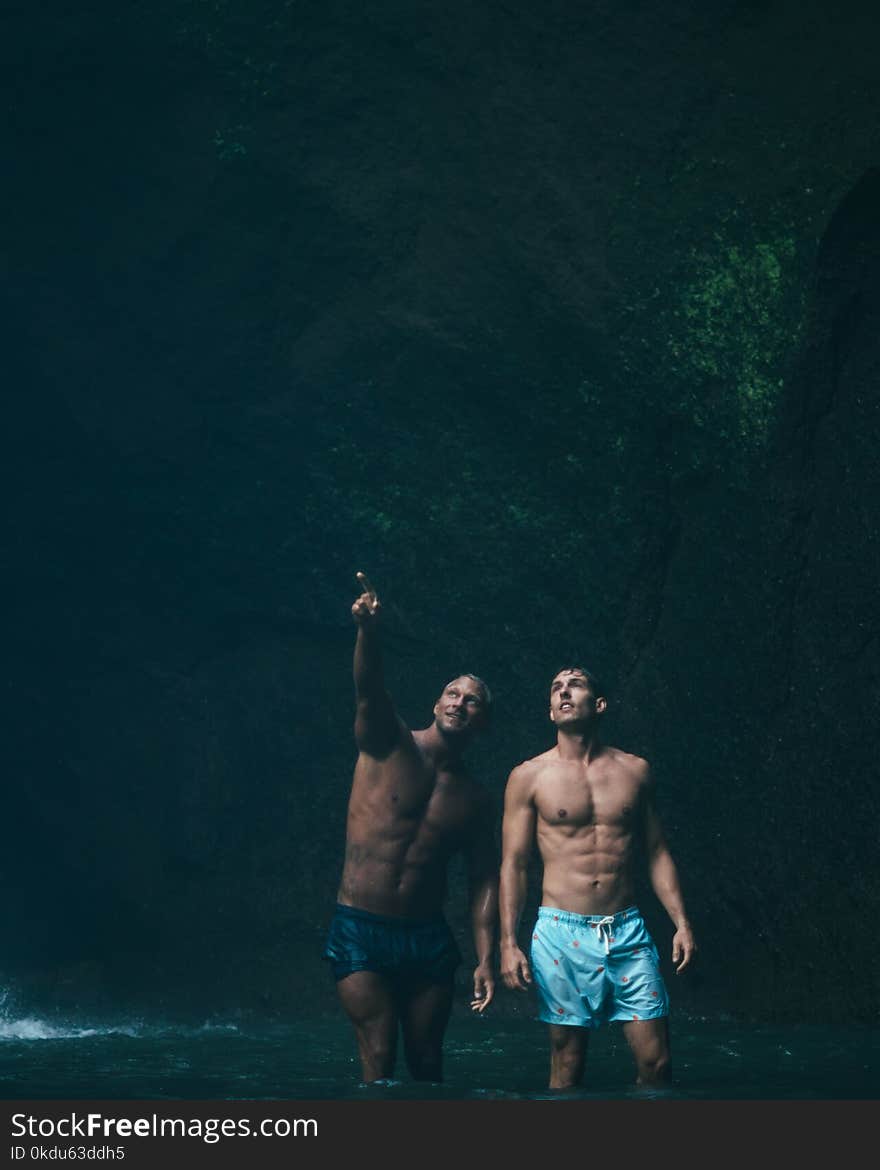 Two Men in Blue Shorts on Body of Water